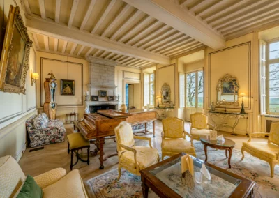 Grand salon jaune pastel agencé avec du mobilier du 18e siècle et d'un magnifique piano à queue en acajou.